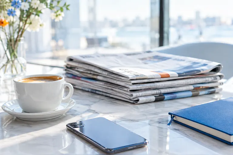 Pile de journaux pliés sur une table de café, relations presse et liens éditoriaux